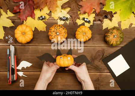 We make gifts for Halloween. Making a funny bat out of a small yellow pumpkin. Halloween party decor. DIY instruction. Step by step guide. Ready. Stock Photo