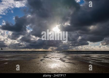 dramatic dark clouds over beach at low tide Stock Photo