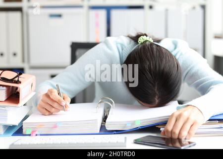 Tired woman lies on folder with documents on table in office Stock Photo