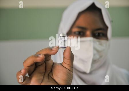 Sylhet, Bangladesh. 14th Oct, 2021. Medical staff holding a vial of the Pfizer-BioNTech Covid-19 Vaccine at the M A G Osmani medical college & hospital vaccination center. Credit: Majority World CIC/Alamy Live News Stock Photo