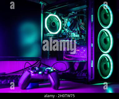 Game controller and pc rgb case on a wooden desk with green and purple lights Stock Photo