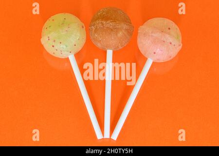 Set of lollipops on orange background. Big bright tasty lollipops on white sticks on orange background with copy space. Sweet candy concept Stock Photo