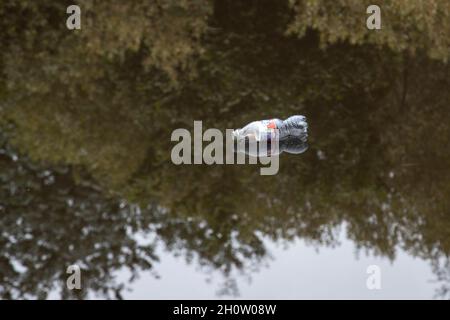 DIscarded plastic soft drinks bottle floating in a canal and adding to the plastic pollution causing pressing environmental issues on the planet Stock Photo