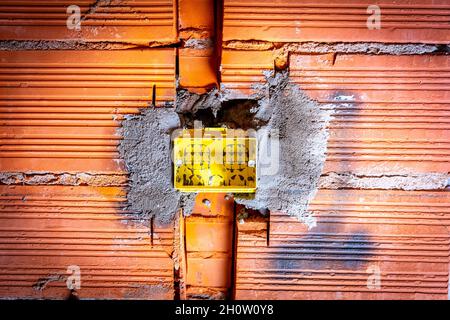 Close up of a yellow box for electrical plugs installation on an orange box Stock Photo