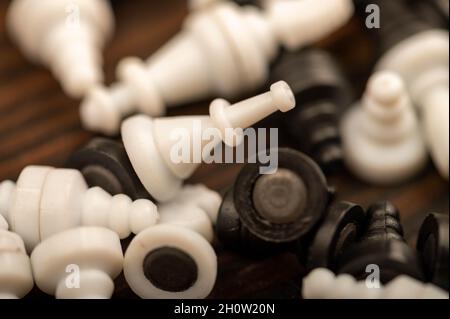 Black and white chess pieces scattered on a wooden table, close-up, selective focus Stock Photo