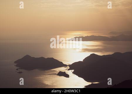 beautiful aerial panorama from the Babadag peak of high mountains rising up over the Mediterranean sea at sunset near Oludeniz Blue Lagoon coast in Tu Stock Photo