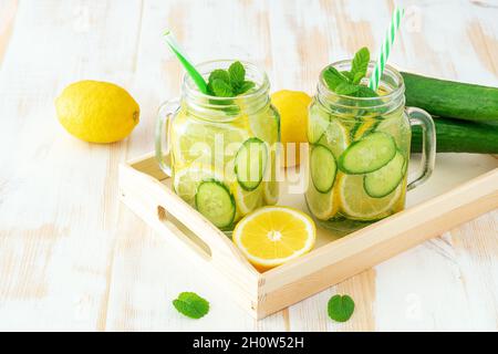 Detox water with sliced lemon and cucumber in a jar on wooden table. Healthy concept. Stock Photo