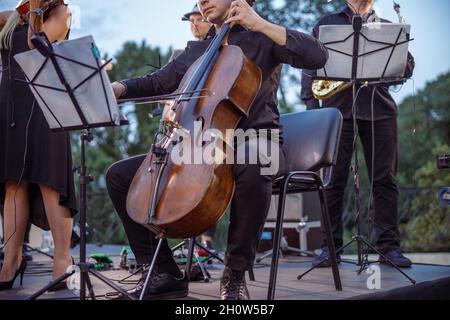 Male musician playing violoncello in orchestra on the street Stock Photo