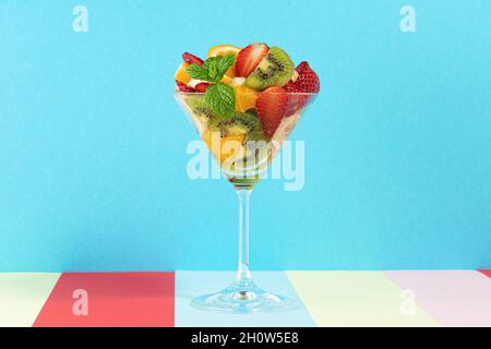 Fruit cocktail in martini glass on bright background. Minimal food vegan concept. Stock Photo