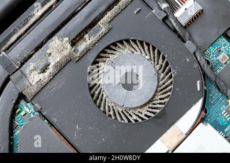 Close-up detail view of disassembled laptop pc motherboatd with dirty dust chip gpu cooling fan part. Fixing computer overheating. Professional Tech Stock Photo