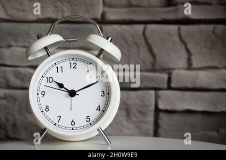 small white retro alarm clock with a grey stone background and copy space Stock Photo