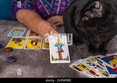 older white-haired woman reading tarot cards on a wooden table with candle Stock Photo
