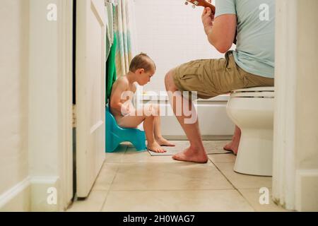 Four year old boy learning to potty train with dad helping Stock Photo