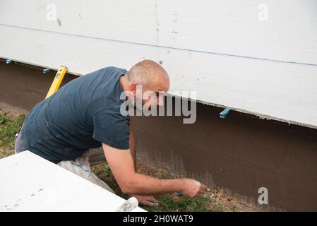 Construction worker checking straightness of styrofoam boards Stock Photo