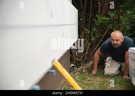 Construction worker checking straightness of glued isolation boards Stock Photo