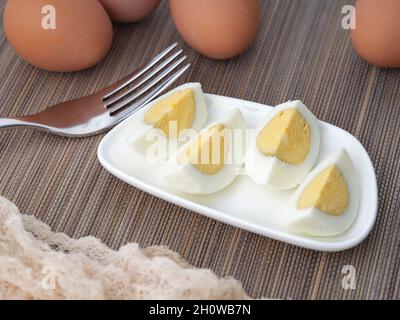 Sliced up hard boiled eggs on a small plate with a fork near them. Close up Stock Photo