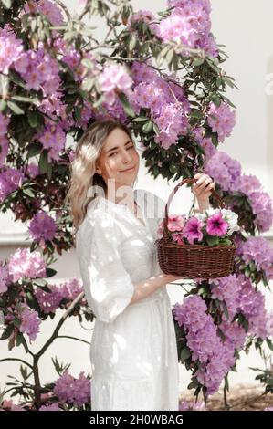 Romantic girl with a basket in the rhododendron bushes. Stock Photo