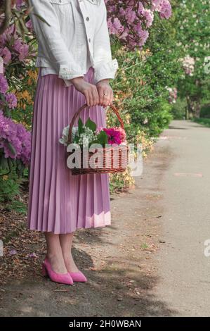 A basket with lilies of the valley and petunias in the hands. Stock Photo