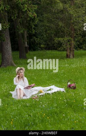 Girl with a book on a blanket in the forest. Stock Photo