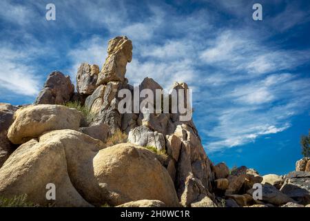 Towering rock formation with a cloud sky in the California Mojave Desert Stock Photo