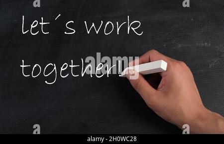 Lets work together is standing on a chalkboard, handwritten with white chalk Stock Photo