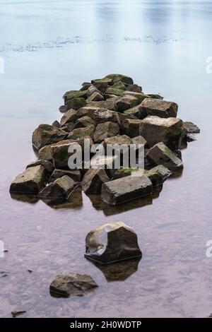 Pile of heavy basalt blocks in the water of a dutch river Stock Photo