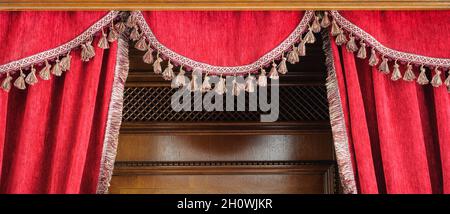 Red velvet curtain with tassels, braids and fringe Stock Photo