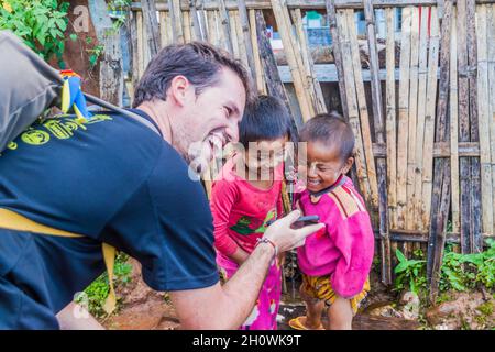 HSIPAW, MYANMAR - DECEMBER 1, 2016: Tourist is showing a photo to local children in a village near Hsipaw, Myanmar Stock Photo