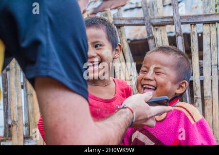 HSIPAW, MYANMAR - DECEMBER 1, 2016: Tourist is showing a photo to local children in a village near Hsipaw, Myanmar Stock Photo