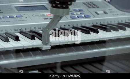 Robotic mechanism plays piano. HDR. Exhibition of robotics with practical performances for demonstration. Primitive robotic hand plays synthesizer. Ex Stock Photo