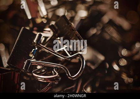 Metal binder clips, also known as foldback clips and bulldog clips, are scattered on a desk, July 20, 2016, in Coden, Alabama. Stock Photo