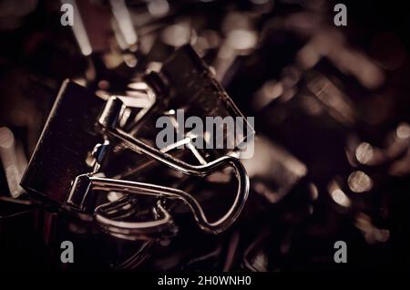 Metal binder clips, also known as foldback clips and bulldog clips, are scattered on a desk, July 20, 2016, in Coden, Alabama. Stock Photo