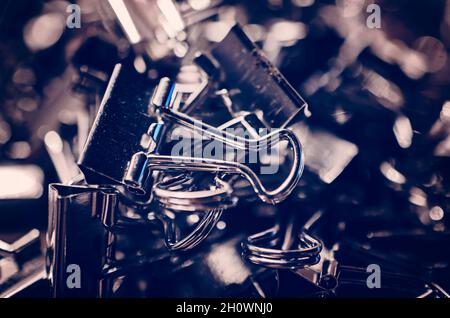 Metal binder clips, also known as foldback clips and bulldog clips, are scattered on a desk, July 20, 2016, in Coden, Alabama. Stock Photo