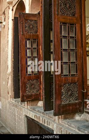 Yazd, Iran, February 19, 2021: High windows with beautiful old wooden folding shutters on the walls of a adobe house, opening up in the courtyard in t Stock Photo