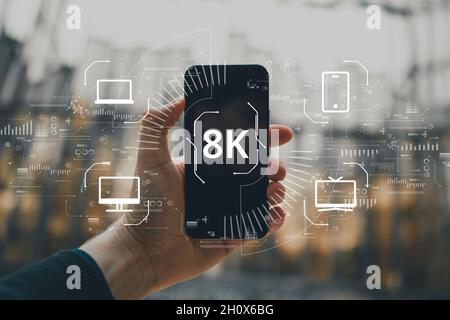 High resolution 8k concept on abstract image with hands and smartphone. Icons computer, tv and smartphone Stock Photo
