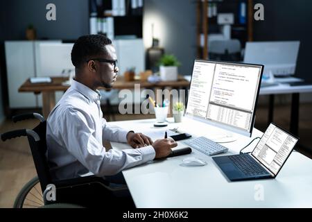 Disabled African Web Developer In Wheelchair Using Computer Stock Photo