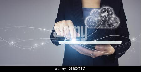 Abstract cloud connection technology background. White tablet in businesswoman hand with digital hologram digital cloud sign and arrow up on grey back Stock Photo