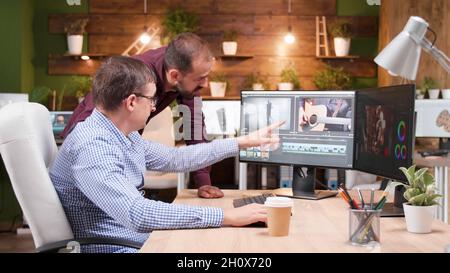 Videographer producer editing film production discussing movie graphic with photographer collegue working in creativity startup company. Focused editor man developing digital footage. Digital industry Stock Photo