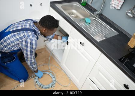 Plumber Drain Cleaning Services In Kitchen. Unclog Blocked Pipe Stock Photo
