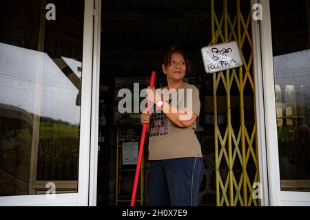 Essential oil producer, Maryline Manczak, waits outside her boutique for passing customers stood beside a sign advising of Covid-19 regulations, as Mauritius unlocks to tourists after 18 months of closed borders and residents encourage people to return to the Indian Ocean island in Africa. Picture date: Monday October 11, 2021. Stock Photo