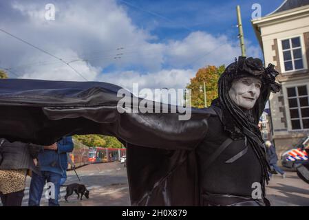 An Extinction Rebellion's silent 'Black-Rebel' stands near the Dutch parliament building during the demonstration.On the fourth-day of climate activities, Extinction Rebellion protesters held a silent march to commemorate the victims of the climate crisis. One-hundred and fifty Extinction Rebellion rebels mostly dressed in black, walked in silence through the streets of The Hague on a four-kilometer march. They carried placards emphasizing the victims of extreme weather during the past year. Leading the silent protest were the 'Black-Rebels', they escorted the funeral procession from the Malie Stock Photo