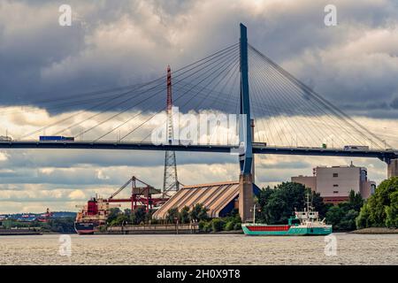River traffic on the Köhlbrand, a secondary branch of the Elbe. The Köhlbrandbrücke is a cable-stayed road bridge in the German city of Hamburg. Stock Photo
