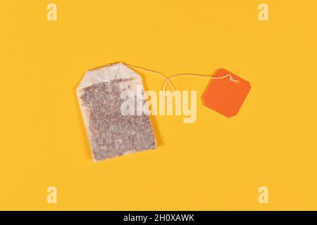 Tea bag with blank orange label on yellow background Stock Photo