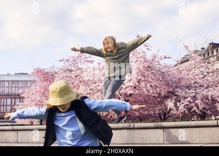 Girls jumping, blossoming cherry trees on background Stock Photo