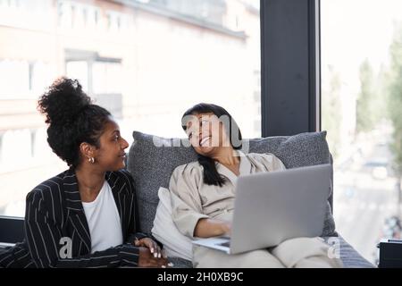 Smiling female coworkers sitting together Stock Photo