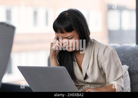 Woman frowning while using laptop Stock Photo