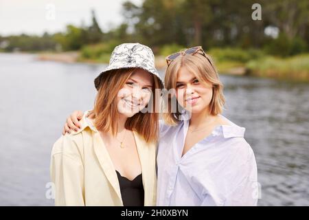 Two friends embracing at lakeside Stock Photo