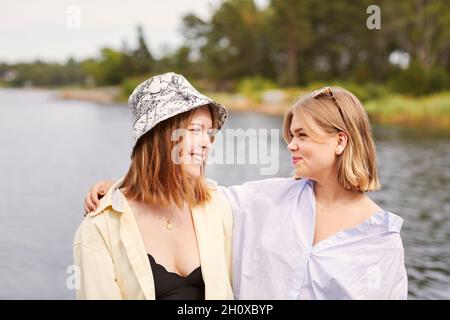 Two friends embracing at lakeside Stock Photo