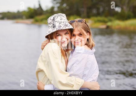 Two friends embracing at lakeside Stock Photo
