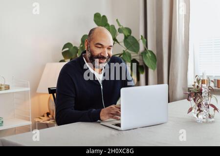 Smiling man using laptop at home Stock Photo